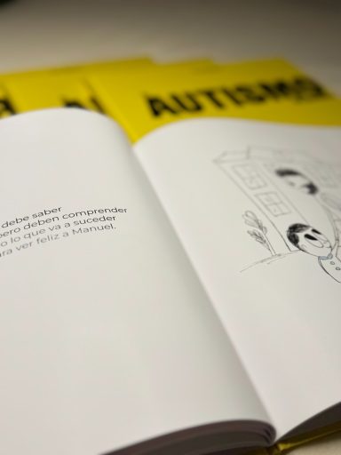 Libro abierto sobre una mesa, con ilustración y texto sobre el autismo. Fondo amarillo.